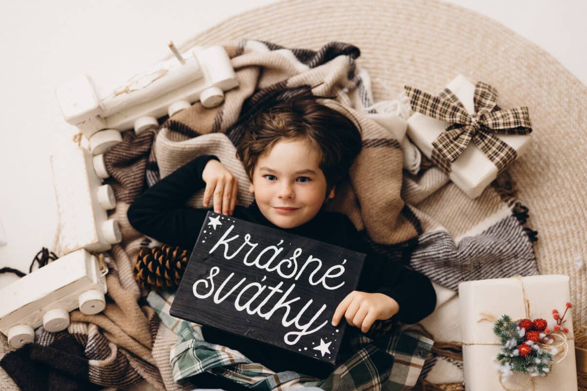 Skutečná fotografie vánočního ateliéru se stromky a cedulkou Veselé Vánoce